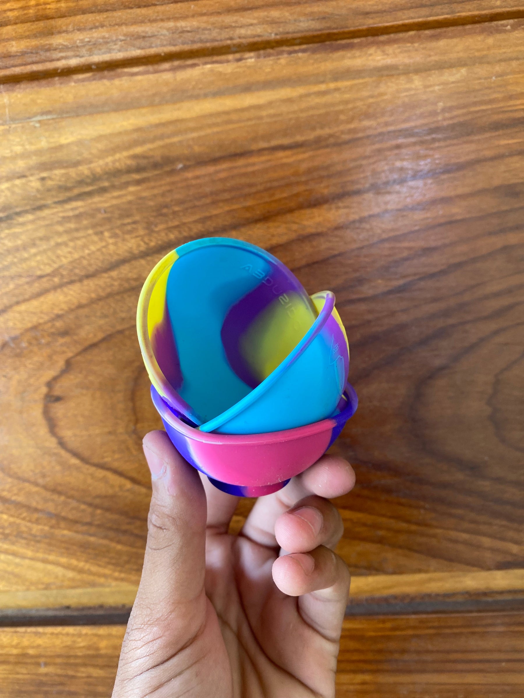 Cuia de silicone colorida em formato de ovo com padrão em cores azul vibrante rosa amarelo e roxo swirl