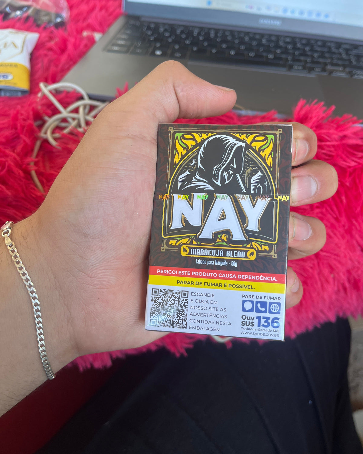 Embalagem retangular preta e dourada de essencia nay sabor maracuja blend com design de figura encapuzada