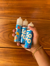 Três frascos de e-líquido juice zomo 60ml 3mg azul e branco com ilustrações de frutas em uma mão contra superfície de madeira
