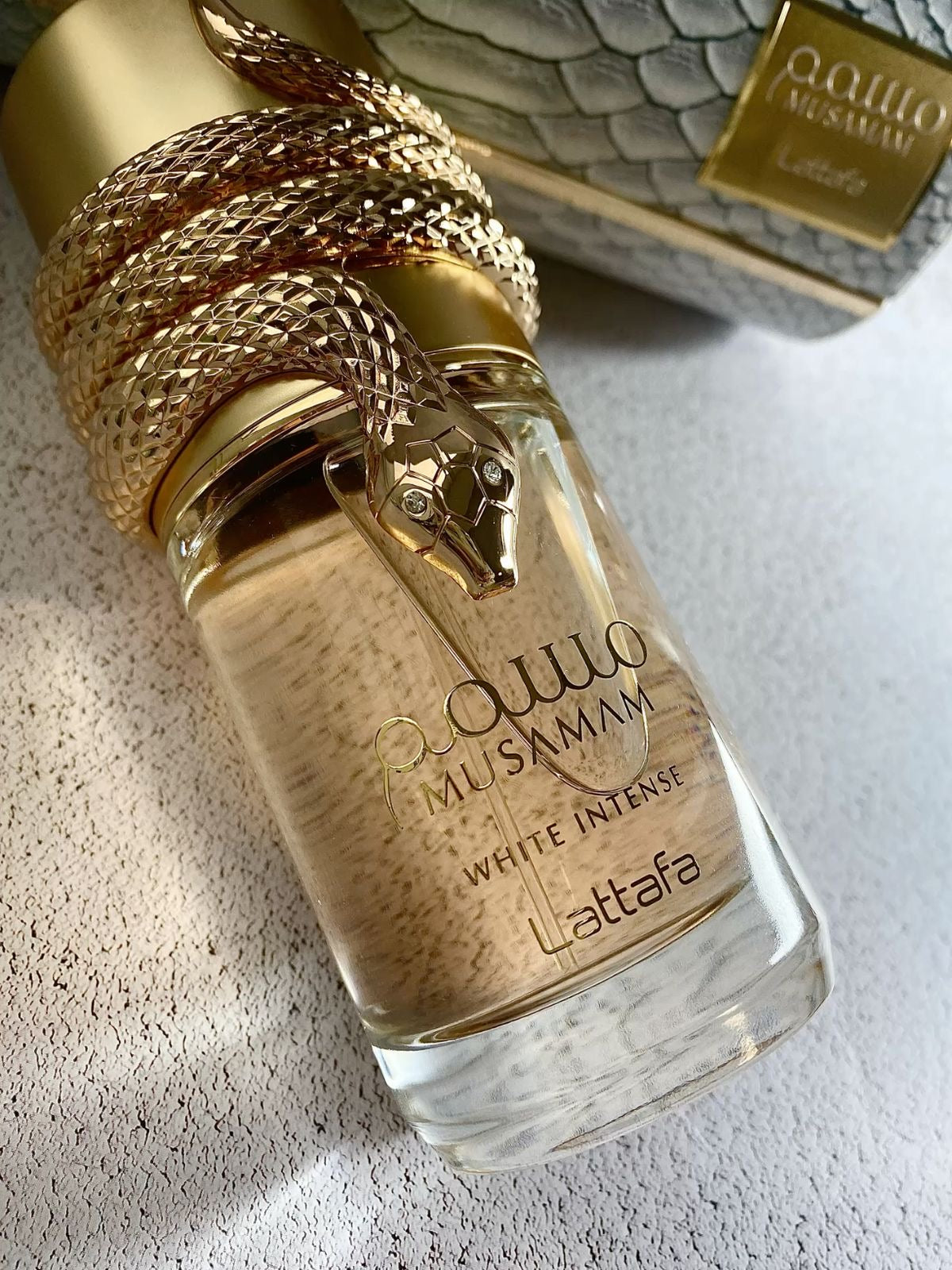 Frasco dourado com cobra para perfume musamam white intense lattafa feminino 100 ml com vidro texturizado e marca em relevo
