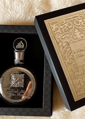 Elegante perfume fakhar black lattafa eau de parfum masculino em frasco prateado com gravação floral e escrita árabe em caixa preta luxuosa