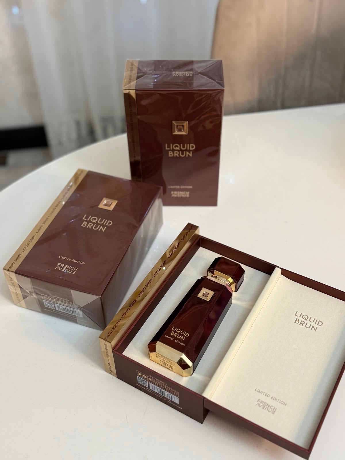 Frasco elegante de vidro vinho com detalhes dourados e tampa combinando em caixa aberta de perfume liquid brun french avenue masculino