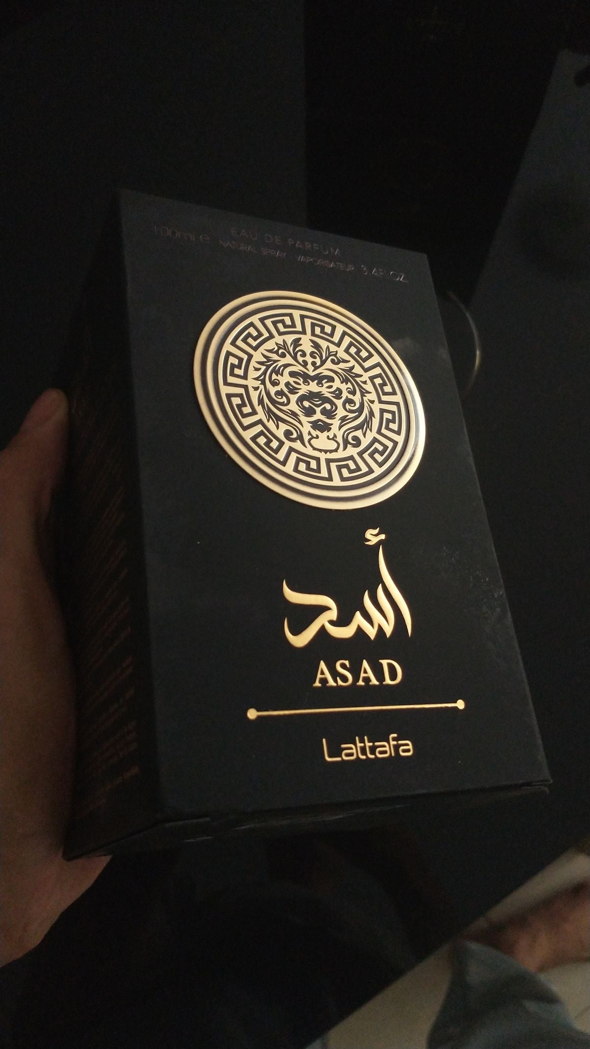 Black rectangular perfume box with gold foil ornate emblem and asad brand name in arabic and english for 100ml eau de parfum