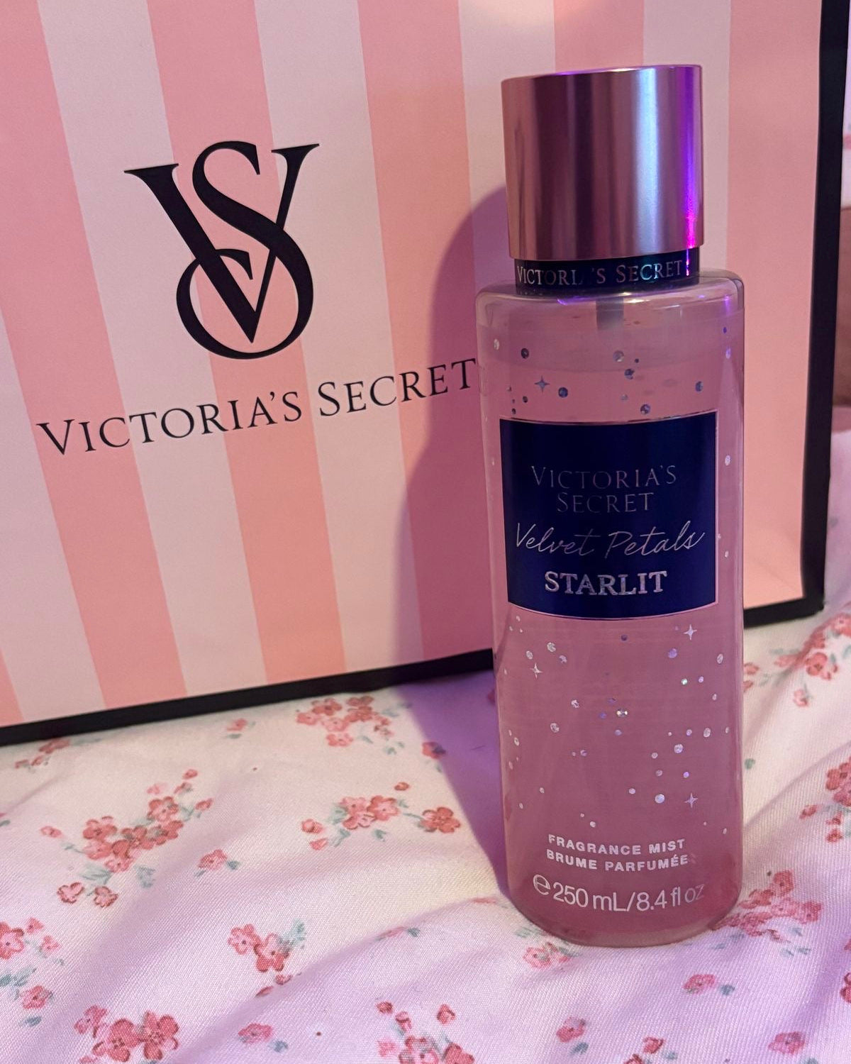 Frasco rosa do perfume corporal velvet petals starlit da victorias secret com tampa prata metálica e brilho interno