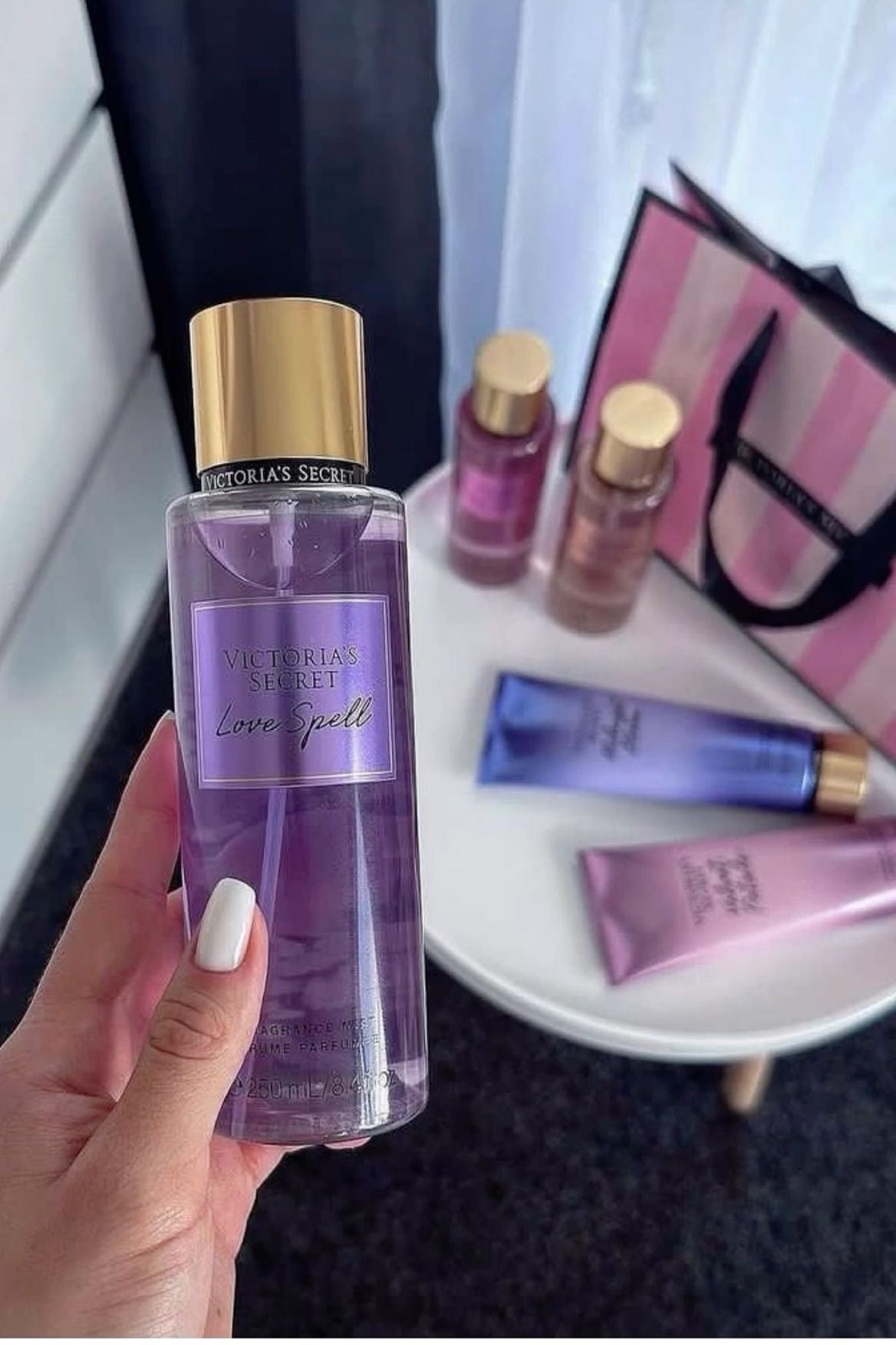 Garrafa de vidro transparente com tampa dourada e rótulo roxo do body splash victoria’s secret love spell 250ml