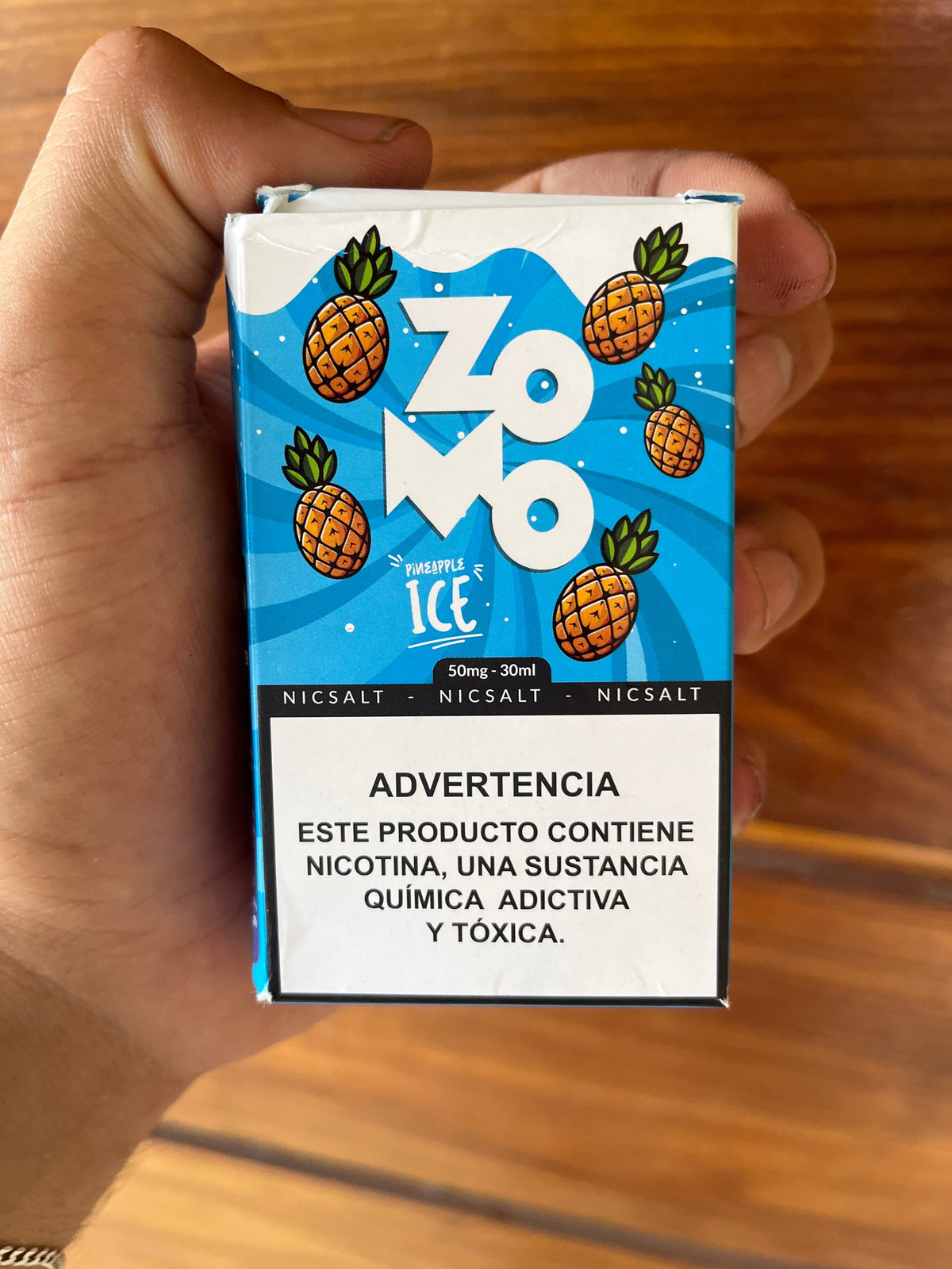 Embalagem azul retangular de e-líquido zomo pineapple ice nicsalt 30ml 50mg com ilustrações de abacaxis cartoons